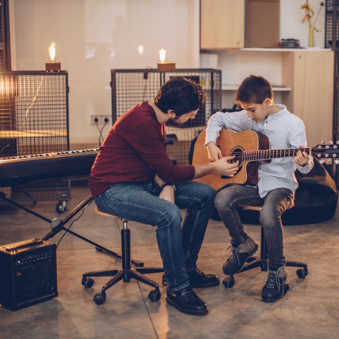 Gitarrenlehrer mit seinem Schüler im Tonstudio beim Üben.