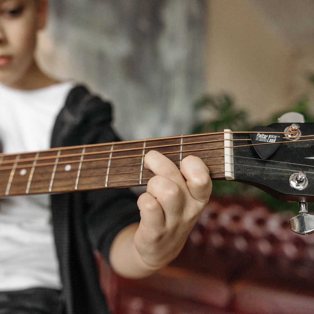 Ein Kind beim Üben von Griffen auf der Gitarre.